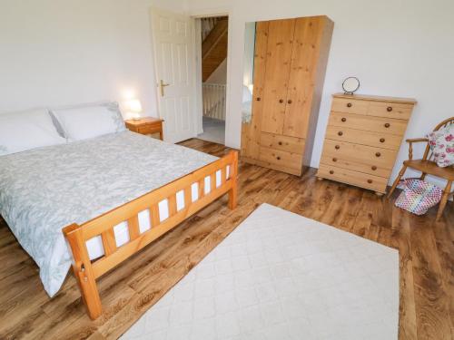 a bedroom with a bed and a dresser at Craiglea Cottage in Coleraine