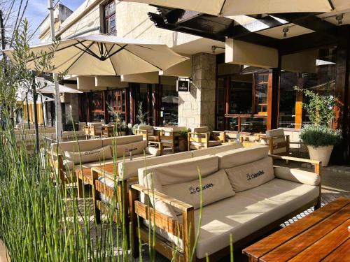 ein Restaurant mit Sofas, Tischen und Sonnenschirmen in der Unterkunft Coronado Hotel in Mina Clavero