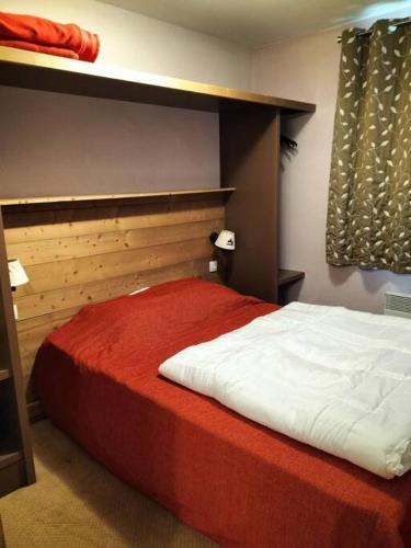 une chambre avec un grand lit avec une couverture rouge dans l'établissement Magnifique T4 pied des pistes, à Risoul