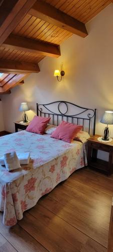 a bedroom with a large bed with pink pillows at Apartamentos Rurales Argame in Argamé