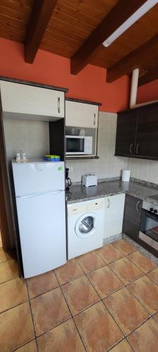 a kitchen with a white refrigerator and a washing machine at Apartamentos Rurales Argame in Argamé