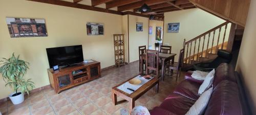a living room with a couch and a flat screen tv at Apartamentos Rurales Argame in Argamé