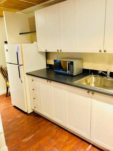 cocina con armarios blancos, fregadero y nevera en Stylish Montreal Apartment: Comfortable Stay in the Golden Square Mile, en Montreal