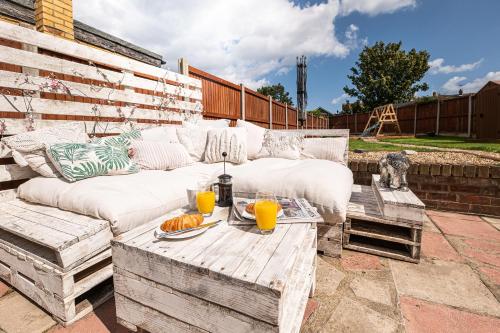 a patio with a white couch and a table with orange juice at Kingsgate Bay Bungalow - 950meter to Beach Dog friendly in Kent