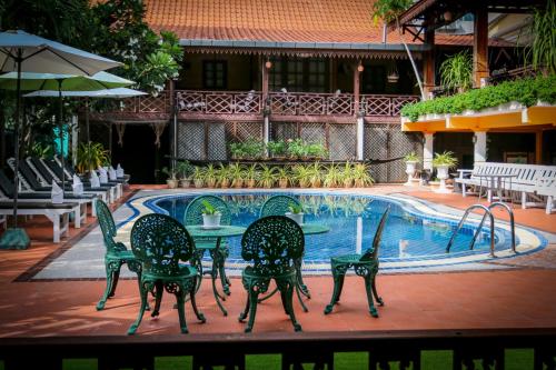 a group of chairs and a table next to a pool at Chandara Boutique Hotel in Vientiane