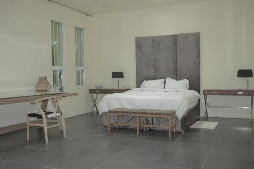 een slaapkamer met een bed, 2 tafels en een bureau bij Industria Villa in Ciudad de Malabo