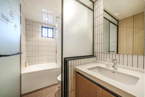 a bathroom with a sink and a tub and a toilet at Brown Dot Hotel Yeonsan in Busan