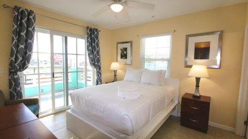 a bedroom with a large white bed and a balcony at Johns Pass Condo's- Fully Remote in St Pete Beach