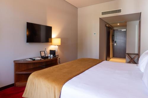 a hotel room with a bed and a desk and a television at Vila Gale Collection Tomar in Tomar