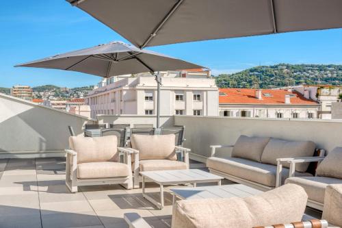 un patio avec des chaises et un parasol sur le toit dans l'établissement REF 1071 - Cannes Center - 5mins to the Palais des Festivals, à Cannes