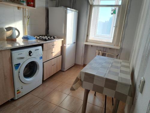 a kitchen with a washing machine and a table at Dacia in Chişinău