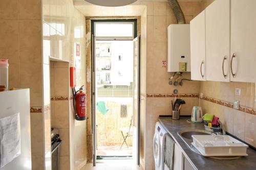 una pequeña cocina con fregadero y ventana en CENTRAL LISBON ROOMS IN PALMIRA SHARED APARTMENT FOR SURF LOVERS, en Lisboa