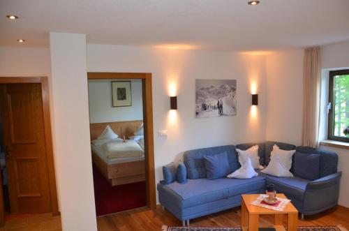 ein Wohnzimmer mit einem blauen Sofa und einem Bett in der Unterkunft Waldheim in Sulden