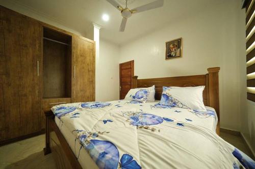 Schlafzimmer mit einem großen Bett mit blauer und weißer Bettwäsche in der Unterkunft Kayla's Court Apartments in Accra