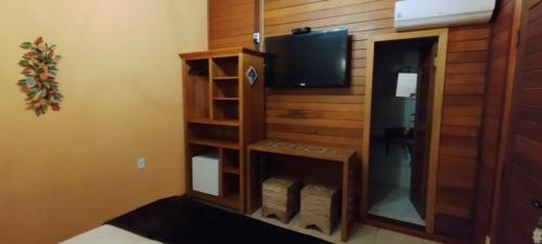 a room with a tv and a shelf with a television at Pousada Sitio das Flores 12 km de Macacos Nova Lima in Nova Lima
