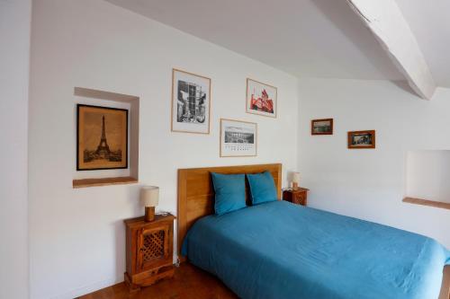 a bedroom with a blue bed and pictures on the wall at Les Airis in Avignon