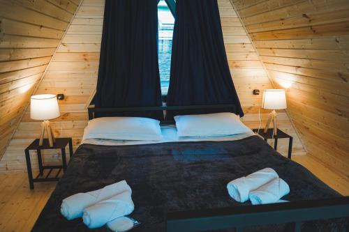 カズベギにあるMisty Rocks Kazbegiのランプ2つ付きの木造の部屋のベッド1台