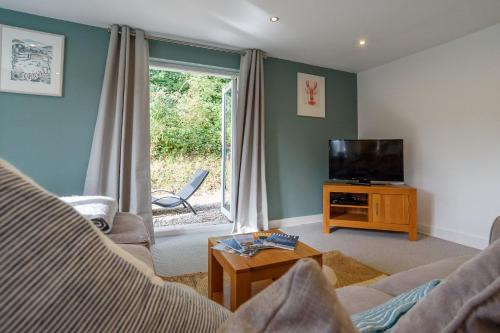 a living room with a couch and a television at Trewhiddle 40 - A Luxury Cottage by Together Travel in St Austell