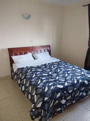 a bedroom with a bed with a blue and white comforter at Ole kerai #101 in Nairobi