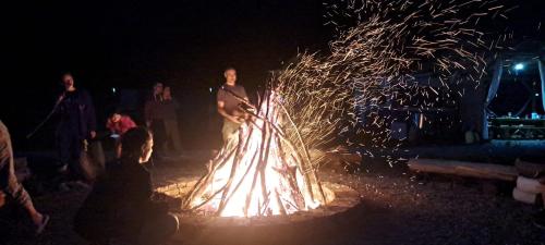 Una donna in piedi accanto a un falò di notte di Forest Glamping a Braşov