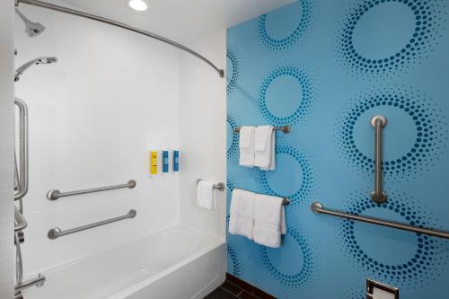 a bathroom with blue walls and a shower with towels at Tru by Hilton Asheville Blue Ridge Parkway in Asheville