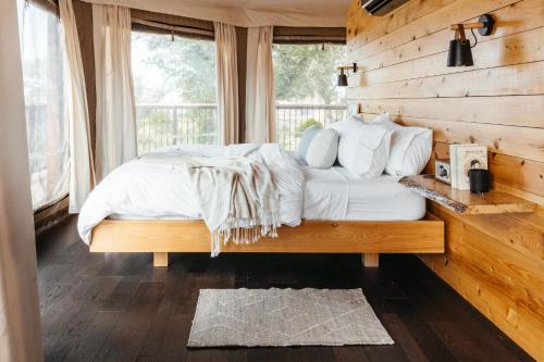 1 dormitorio con 1 cama con pared de madera en Walden Retreats Hill Country, en Johnson City