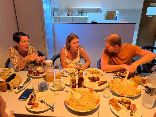 un grupo de personas sentadas alrededor de una mesa comiendo comida en Aasna Inn en Thulusdhoo