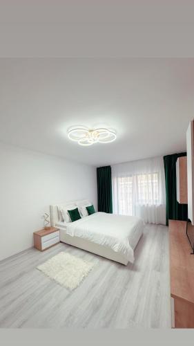 a white bedroom with a bed and a ceiling fan at Scandinavia Apartment 1 in Piatra Neamţ