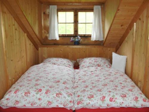 uma cama num pequeno quarto com uma janela em Berghütterl - Ferienhaus Ingerlhof em Tegernsee