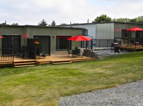 a patio with benches and red umbrellas in a yard at Cribs on the Hill in Picton