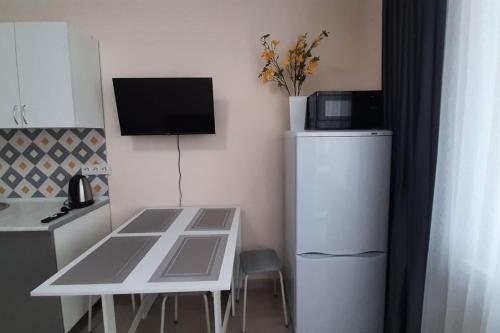 a small kitchen with a table and a white refrigerator at Уютная евродвушка в центре, ЖК Атлант in Almaty