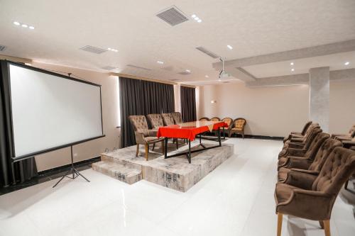 a conference room with a red table and a screen at PREMIER HOTEL in Andijan