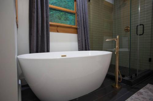a white bath tub in a bathroom with a window at The Ridge: A Modern Cabin in Bostic