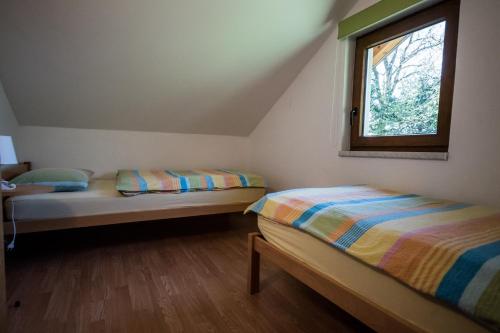 two beds in a small room with a window at Hiša Nataša in Drežnica