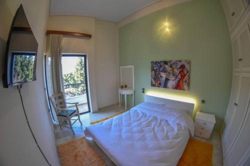 Un dormitorio con una gran cama blanca y una ventana en Lake Plastira Lodge, en Kalyvia