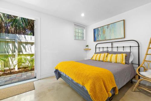 a bedroom with a bed with a yellow blanket and a window at Farmhouse style Home- near Hollywood Beach/ Hot Tub! in Hollywood