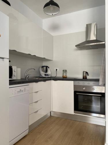 a kitchen with white cabinets and a stove top oven at Coqueto apartamento con Garaje in Santa Cruz de Tenerife