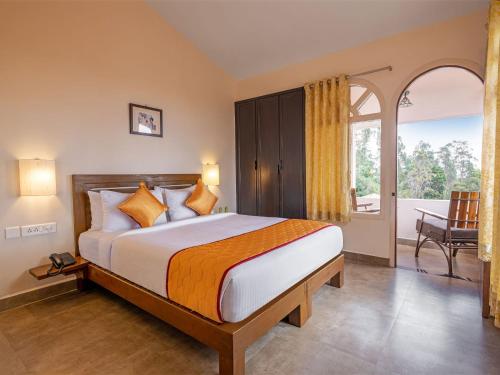 a bedroom with a large bed and a balcony at Mango Hill Kodai in Kodaikānāl