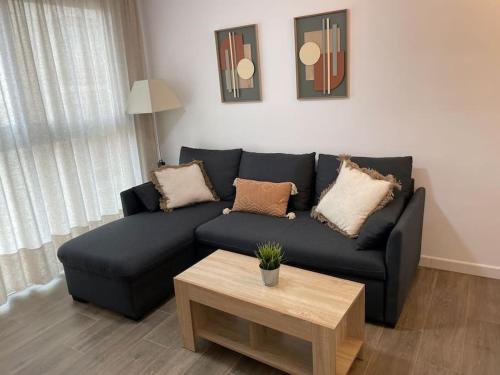 a living room with a black couch and a coffee table at Lovely Beach Apartment in Rincón de la Victoria