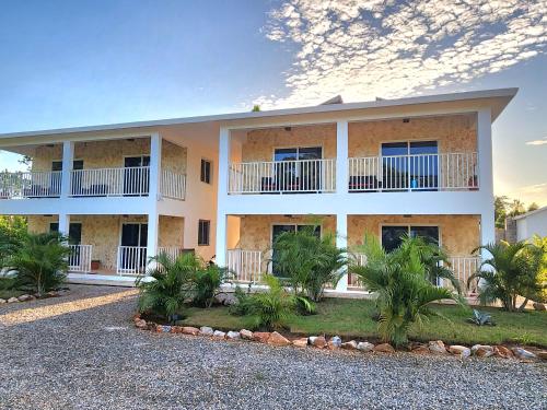 a large white building with palm trees in front of it at Roomy apartment at 5 min walk to the beach in Las Galeras