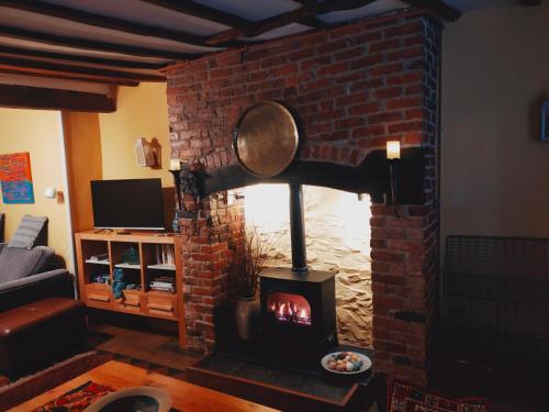 a brick fireplace with a stove in a living room at Spacious ground floor apartment. No 1A The Stables in Llanfyllin