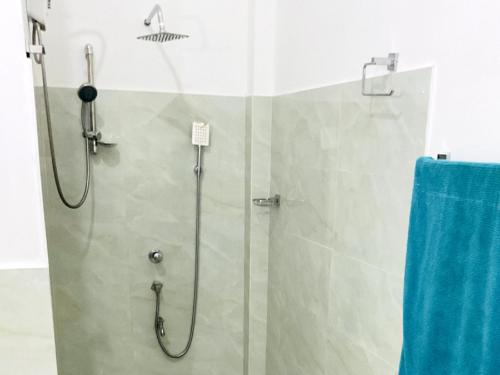 una doccia con porta in vetro e un asciugamano blu di Ayurveda Suwetha Villa a Bentota
