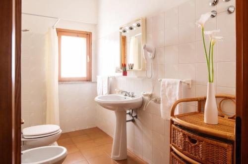 a white bathroom with a toilet and a sink at Hotel L'Aragosta in La Caletta
