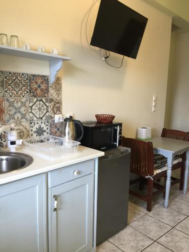 eine Küche mit einem Waschbecken und einem TV an der Wand in der Unterkunft happyWish Syros in Ermoupoli