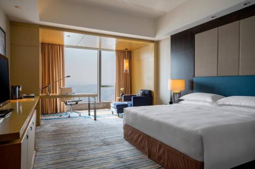 恵州市にあるRenaissance Huizhou Hotelのベッドとデスクが備わるホテルルームです。