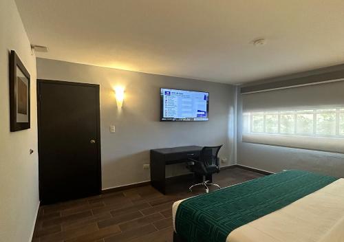 a hotel room with a bed and a desk and a television at InHouse Hotel Obregón in Ciudad Obregón