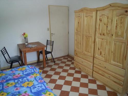 a bedroom with a bed and a wooden cabinet and a table at Habitac Indiv Casa de Familia, Flores in Buenos Aires