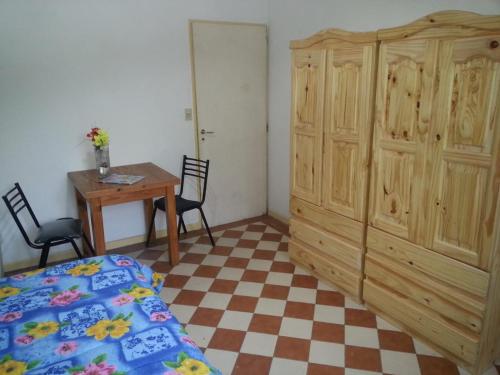 1 dormitorio con 1 cama, armario de madera y mesa en Habitac Indiv Casa de Familia, Flores en Buenos Aires