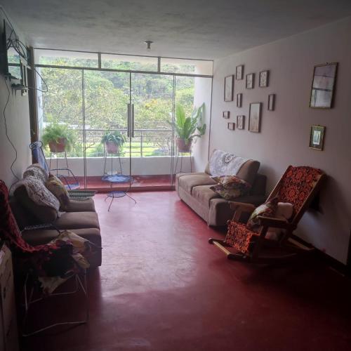 een woonkamer met een bank en stoelen en een groot raam bij HOSPEDAJE MILAGRITOS in Chachapoyas