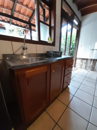 a kitchen with a sink and a large window at Pousada das Palmeiras in Garopaba